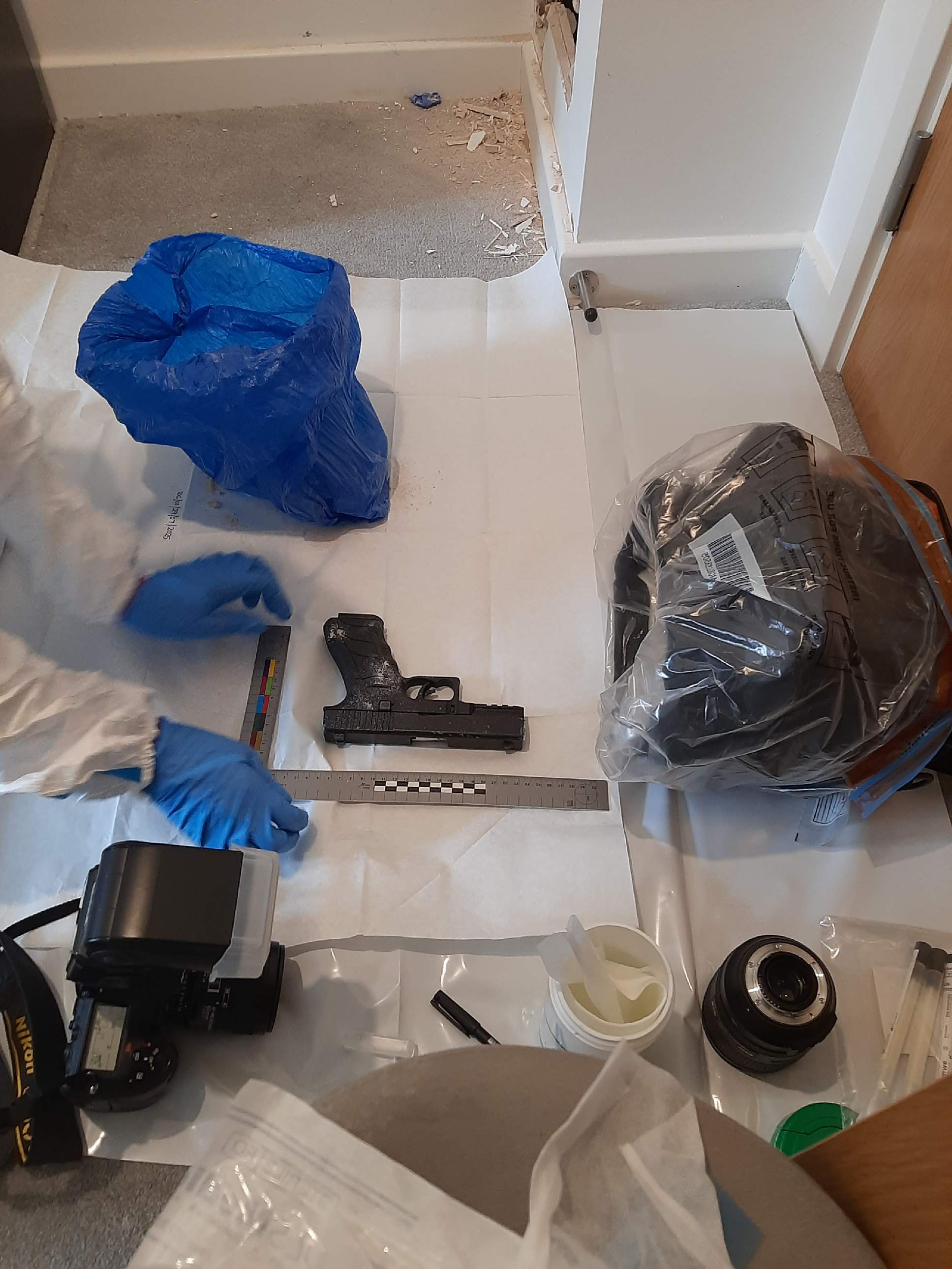 handgun being measured on the floor by forensics
